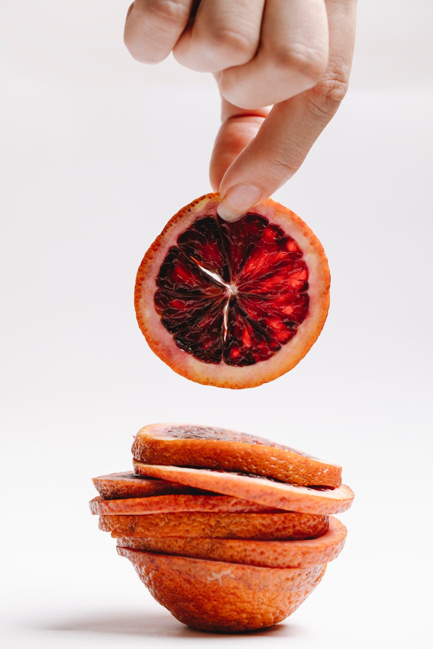 crop woman with slice of red orange