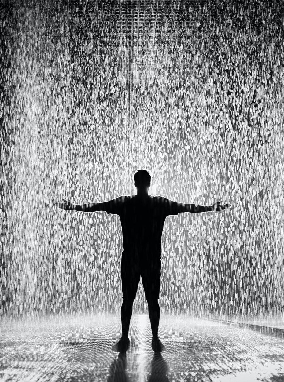 silhouette and grayscale photography of man standing under the rain